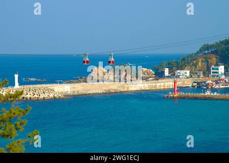 Samcheok City, Corea del Sud - 28 dicembre 2023: Oltre Jangho Bay, due funivie passano l'una accanto all'altra sulle linee vicine, con Jangho Port, le sue due pause Foto Stock