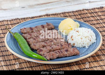 Polpette di inegol di cucina turca. Polpette alla griglia su un piatto. Tekirdag turco o inegol Kofte con pepe, riso e purè di patate, Kofta. Foto Stock