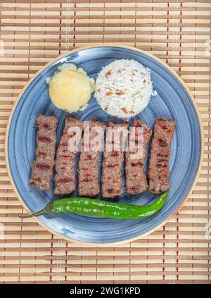 Polpette di inegol di cucina turca. Polpette alla griglia su un piatto. Tekirdag turco o inegol Kofte con pepe, riso e purè di patate, Kofta. Foto Stock