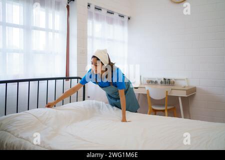 La governante organizza e rende perfetta la biancheria da letto in una camera da letto, la professionalità e la dedizione del personale addetto alle pulizie Foto Stock