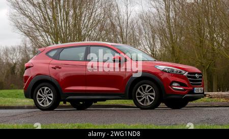 Milton Keynes, Regno Unito - 18 gennaio 2024: 2016 auto Hyundai Tucson rossa che guida su una strada di campagna inglese. Foto Stock