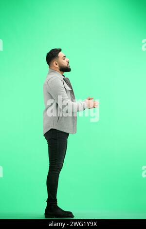 Un uomo, a tutta lunghezza, su sfondo verde, batte Foto Stock