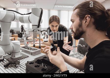 Programma di robotica industriale studenti universitari che imparano l'assemblaggio meccanico con robot Universal Training Platform mod di simulazione braccio robotico Foto Stock