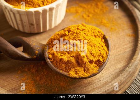 Polvere di radice di curcuma essiccata su un cucchiaio di legno su un tavolo Foto Stock