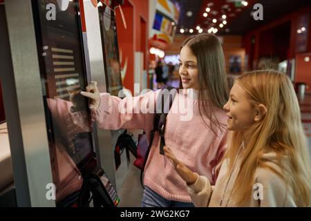 Due ragazze preadolescenti che usano un moderno chiosco self-service nel centro commerciale Foto Stock