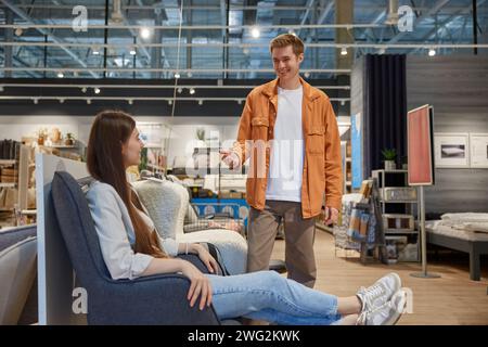 Giovane coppia di famiglie che sceglie una comoda sedia per gli interni di casa Foto Stock