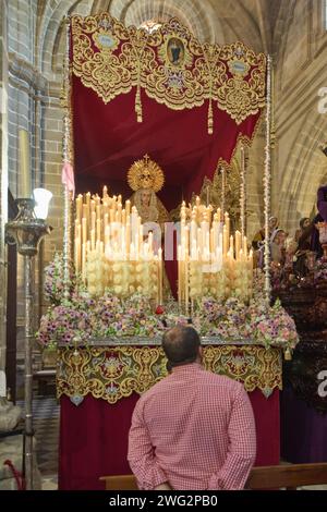 Jerez de la Frontera, Spagna - 01 febbraio 2024: Uomo con grande devozione di fronte ad un passaggio della settimana Santa in Spagna con la Vergine circondata da illuminata ca Foto Stock