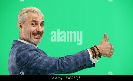Un uomo, primo piano, su sfondo verde, mostra i pollici in alto Foto Stock