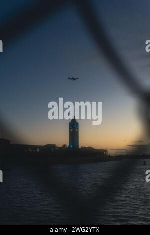 Foto di un aereo che vola sulla Aloha Tower durante il tramonto a Honolulu Hawaii Foto Stock