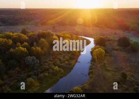 Splendido paesaggio con fiume, prato e alberi sotto i raggi del sole che sorge la mattina presto all'alba dalla vista aerea. Foto Stock