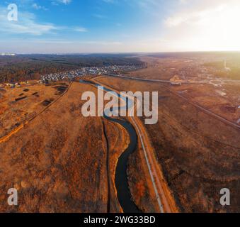 Fiume tortuoso nel campo con erba secca. Paesaggio autunnale dalla vista aerea. Foto Stock