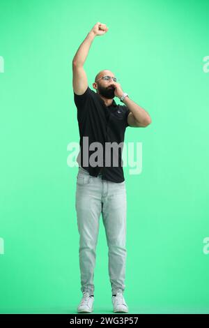 Un uomo, su sfondo verde, a piena altezza, si rallegra Foto Stock