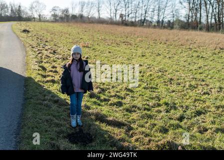 Bambina in abiti invernali in piedi in mezzo a un prato Foto Stock