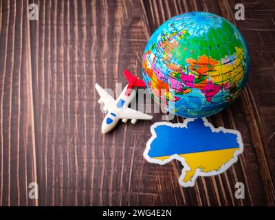 Vista dall'alto flay ucraina, aeroplano giocattolo e globo terrestre su sfondo in legno. Foto Stock