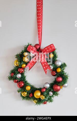 Corona di Natale con nastro rosso con stelle e decorazioni con palle natalizie dorate, rosse e argento. Foto Stock