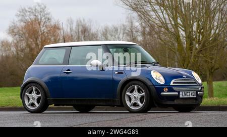 Milton Keynes, Regno Unito - 18 gennaio 2024: Auto d'epoca Mini Cooper blu 2002 che guida su una strada di campagna inglese. Foto Stock