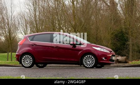 Milton Keynes, Regno Unito - 2 febbraio 2024: 2009 auto Ford Fiesta rossa che guida su una strada di campagna inglese. Foto Stock