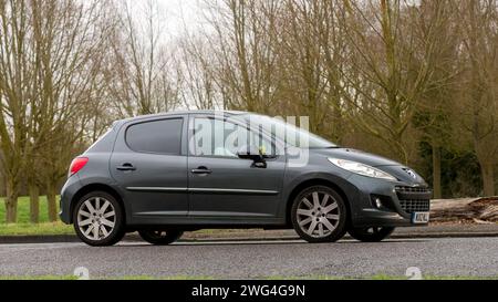 Milton Keynes, Regno Unito - 2 febbraio 2024: 2012 Peugeot 207 grigia che guida su una strada di campagna inglese. Foto Stock