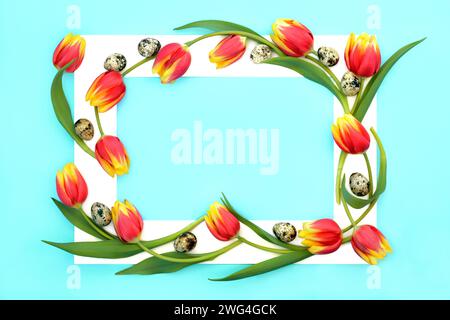 Uova di quaglia con fiori di tulipani rossi e gialli con cornice bianca. Composizione astratta su sfondo blu pastello. Design floreale per la primavera e la Pasqua. Foto Stock