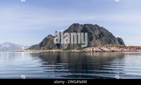 Un tranquillo panorama delle aspre isole Lofoten in Norvegia, dove vette frastagliate perforano il cielo sopra acque tranquille, riflettendo una sinfonia della natura Foto Stock