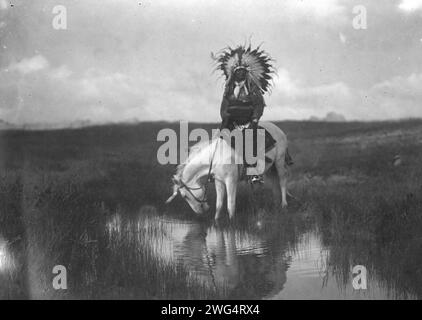 La Valle del Rosebud, c1905. La foto mostra un indiano Cheyenne, che indossa un copricapo di guerra, a cavallo in una piscina d'acqua. Foto Stock