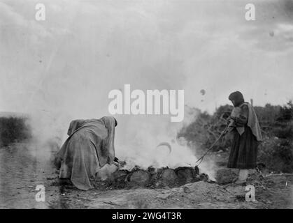 Bruciatori di ceramica a Santa Clara, c1905. La fotografia mostra due donne, probabilmente Tewa, che curano una fossa di fuoco, Santa Clara Pueblo, New Mexico. Foto Stock