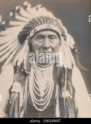 Joseph-Nez PERCé, c1903. La fotografia mostra il capo Giuseppe, un ritratto a metà lunghezza, rivolto verso la parte anteriore, che indossa un cofano da guerra e diverse collane. Foto Stock