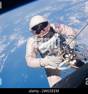 Gemini 4 Astronaut ed White, il primo americano ad eseguire attività extraveicolare, galleggia a gravità zero a nord-est delle Hawaii. Attaccata alla capsula Gemini 4 da un laccetto rivestito con nastro dorato e da un'unità di manovra manuale (HHSMU) o "pistola a cerniera" nella mano destra. Questa foto ora iconica è stata scattata dagli astronauti James McDivitt il 3 giugno 1965. Foto Stock