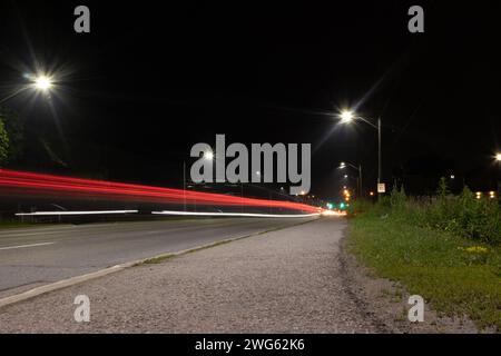 Il paesaggio urbano notturno - luci luminose - sentieri di luce rossa e bianca attraversano la strada - oltrepassando veicoli esposti a lungo. Preso a Toronto, Cana Foto Stock