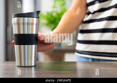 Con una tazza da caffè da viaggio in una camicia a righe Foto Stock