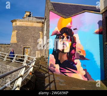 Murale di una donna con occhiali scuri che si gode il sole sulla parete di un edificio sull'isola di Knightstone a Weston super Mare Foto Stock