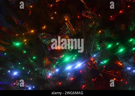 Bellissimo albero di Natale, pino naturale con lampadine a LED rosse, blu, verdi e gialle, bellissime palle, giocattoli. Vacanze di Capodanno, Natale e Capodanno. Foto Stock
