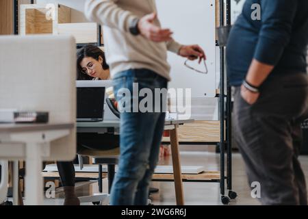 Professionale femminile concentrata che lavora su un notebook in un ufficio affollato Foto Stock