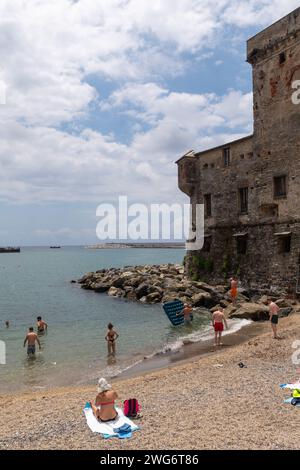 Gente che prende il sole sulla piccola spiaggia del Castello di Rapallo, costruito nel 1551 per difendere la città dai pirati saraceni, Rapallo, Genova, Liguria, Italia Foto Stock