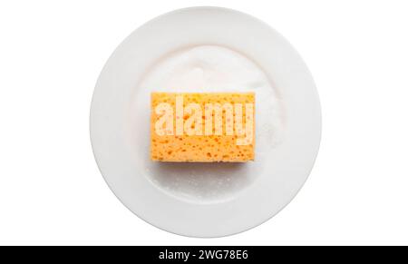Spugna gialla per la pulizia su una piastra bianca con schiuma di sapone isolata su uno sfondo bianco. Utilizzare una spugna per strofinare e lavare le macchie di cibo e la sporcizia Foto Stock