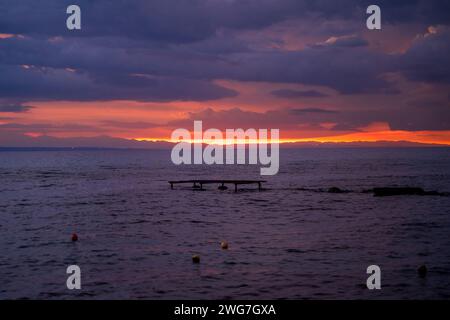 Foto a lunga esposizione di un'alba o di un tramonto su un corpo d'acqua marino contro le nuvole drammatiche situate a Drosia, Zakinthos, Grecia Foto Stock