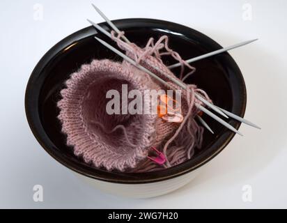 lavorazione a maglia con lana rosa e aghi per maglieria in un recipiente di ceramica Foto Stock