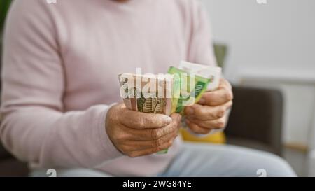 Un uomo di mezza età conta i rubli russi in un accogliente salotto. Foto Stock