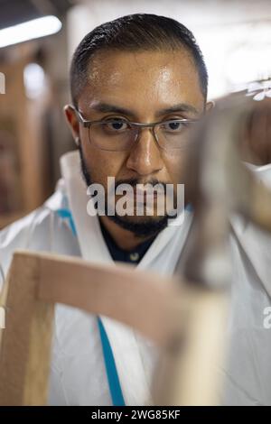 costruzione di mobili in legno negli interni della fabbrica, giovane uomo che usa il martello per riparare e costruire, stile di vita del lavoratore artigianale nella falegnameria, utensile Foto Stock