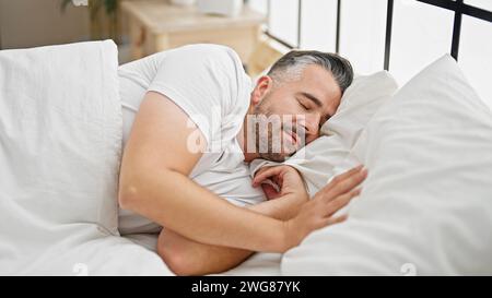 Uomo dai capelli grigi sdraiato sul letto che dorme in camera da letto Foto Stock