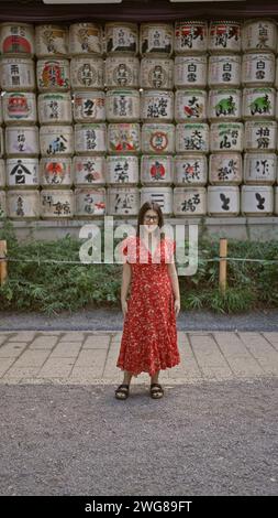 Splendida donna ispanica, radiosa di gioia, posa giocosamente con gli occhiali all'iconico santuario meiji di tokyo, trasmettendo positività e sicurezza. Foto Stock