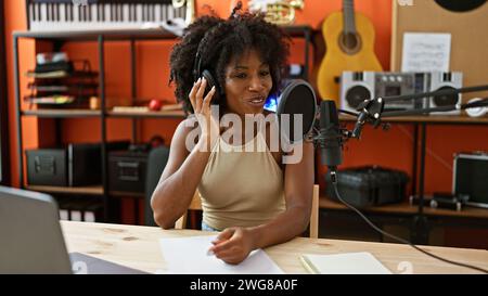 Giornalista radiofonica afro-americana che indossa cuffie che parla allo studio radio Foto Stock