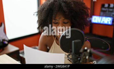Giornalista radiofonica afro-americana che legge sceneggiatura in studio radiofonico Foto Stock