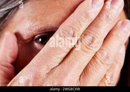 Primo piano di una donna matura con la mano che copre un occhio Foto Stock