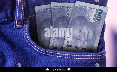 Un mucchio di banconote da 100 Rand del Sudafrica in una tasca di jeans un concetto di spesa Foto Stock