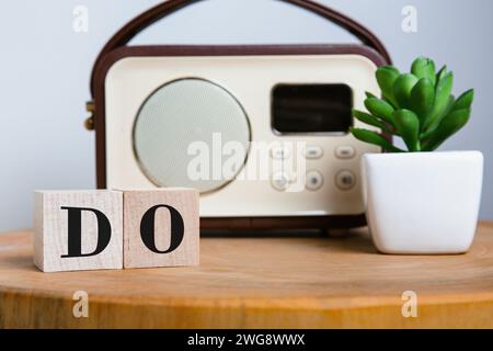 La parola SI pronuncia in lettere a blocchi di legno, azione stimolante, accompagnata da una radio vintage e da una pianta fresca e succulenta su un tavolo rotondo. Foto Stock