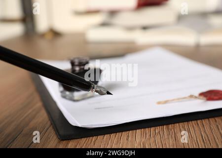 Firma documento con penna stilografica su tavolo di legno, primo piano. Contratto notaio Foto Stock