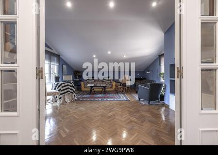 Soggiorno con soffitti inclinati, pavimenti in parquet di quercia e falegnameria in legno bianco Foto Stock