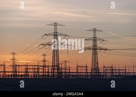 File di piloni ad alta tensione si estendono fino al crepuscolo, sottostazione di Wolmirstedt, Sassonia-Anhalt, Germania Foto Stock