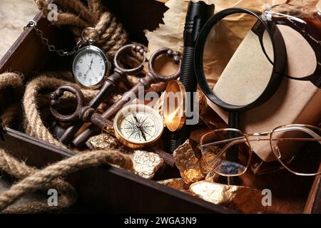 Scatola di legno con attrezzatura da viaggio, pepite dorate e bottiglia di rum, primo piano Foto Stock